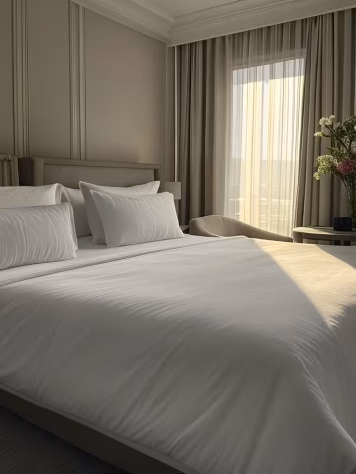 Luxurious hotel bedroom suite with ocean views, king bed with premium linens, morning light streamin