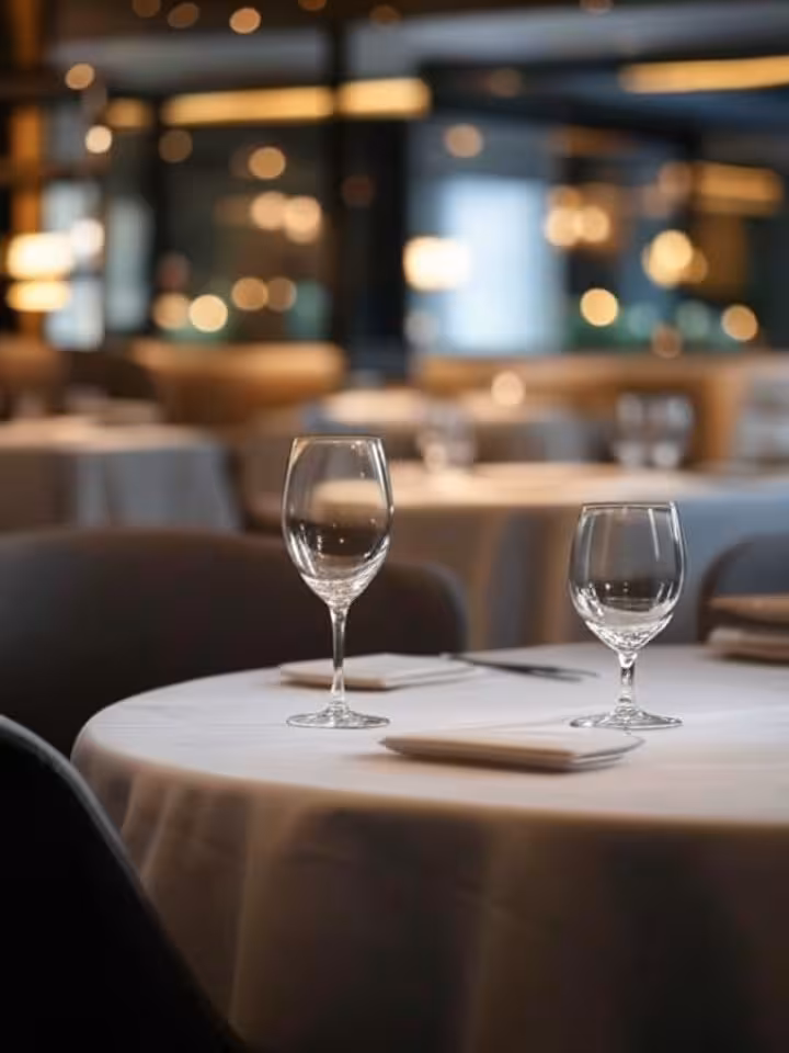 Elegant intimate restaurant interior with soft warm lighting, modern sophisticated decor, two empty