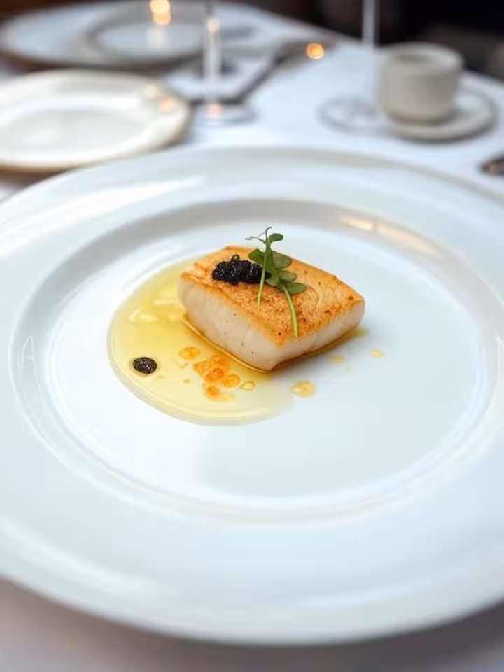 Exquisite seafood dish presentation on white porcelain, artistic plating with caviar and microgreens